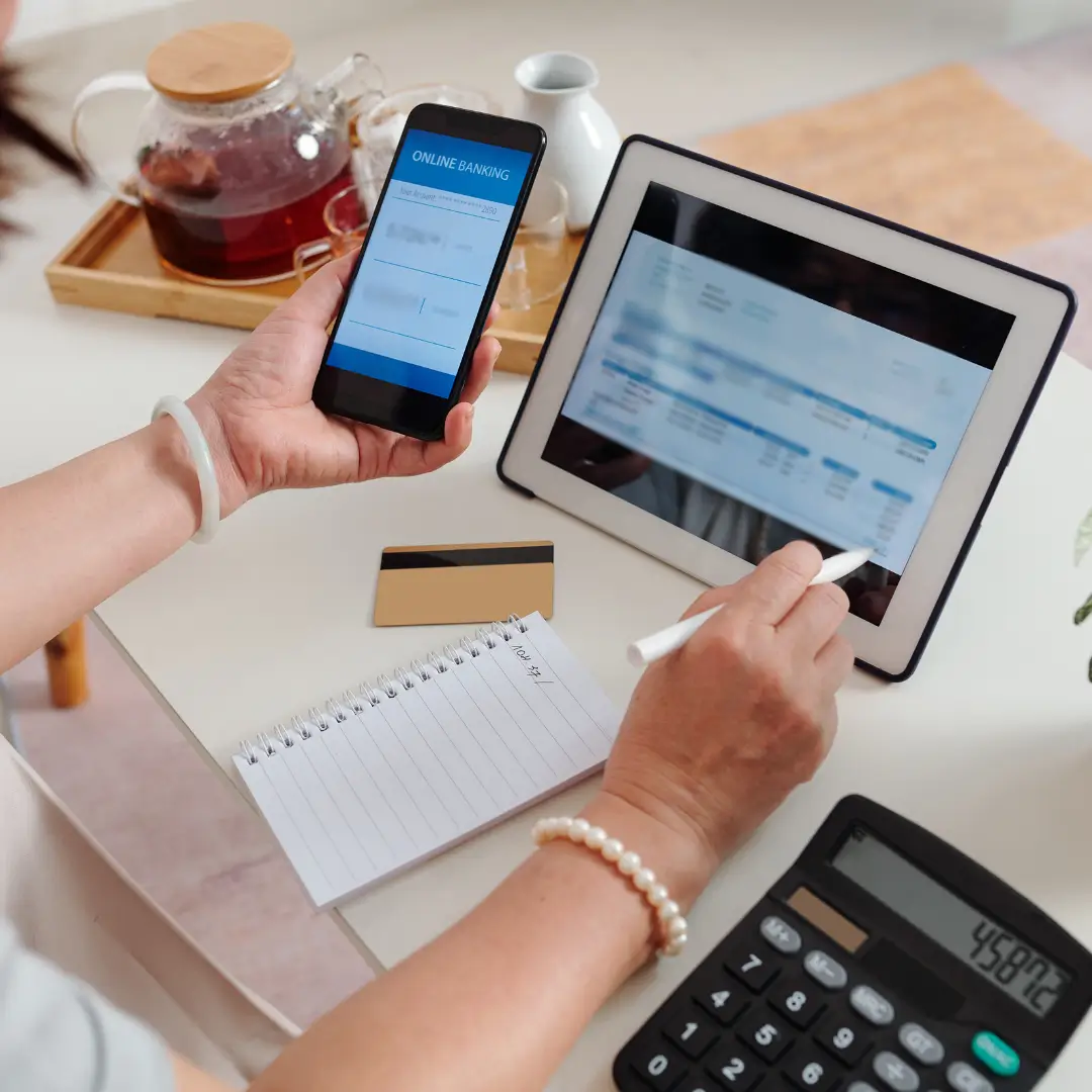 Person managing finances using phone and tablet.